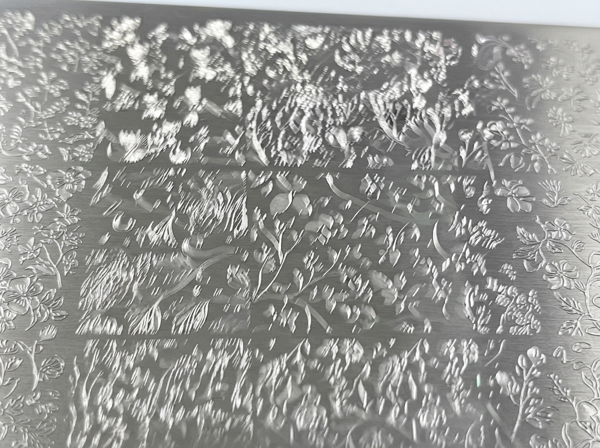 A close-up view of a metal stamping plate engraved with detailed floral designs.