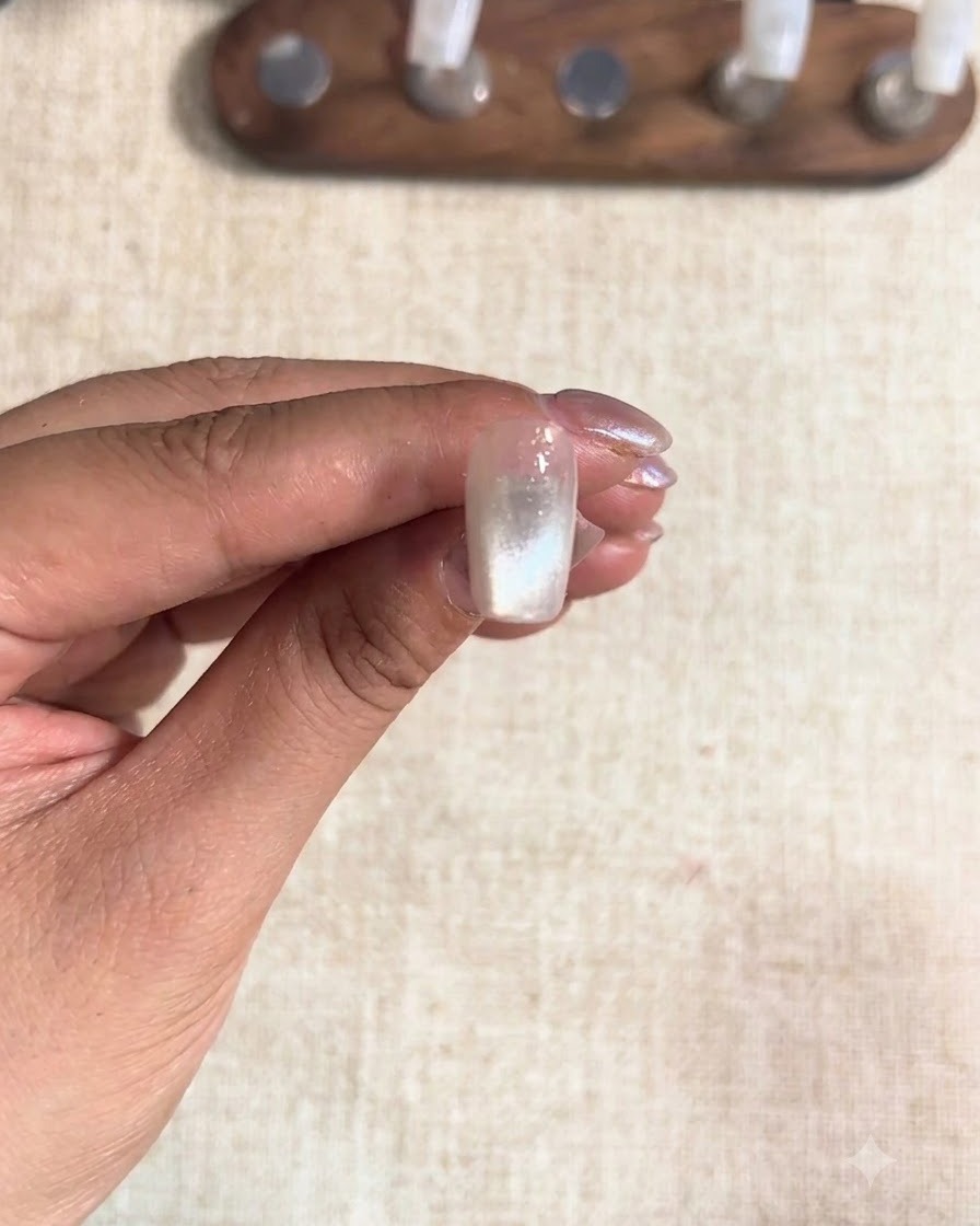 A middle fingernail cured under a lamp, showing a set cat-eye finish.
