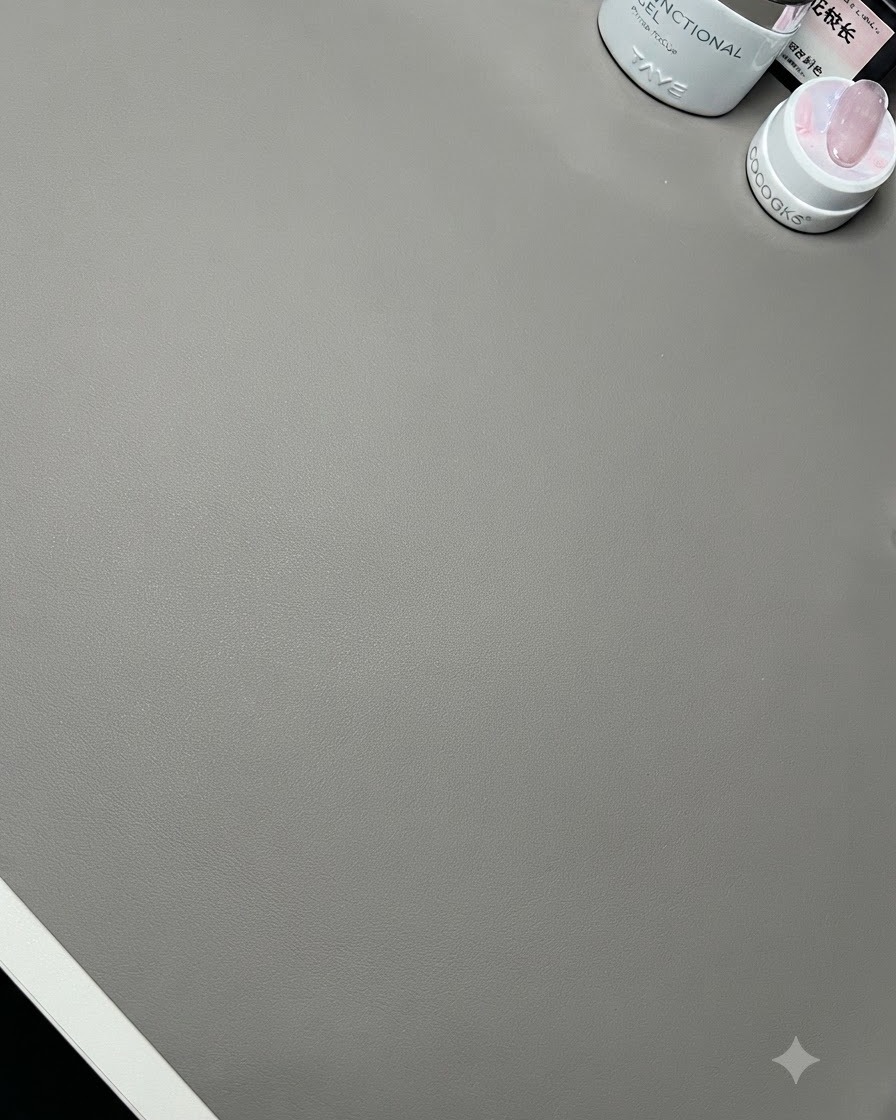 A close-up view of a clean desk surface with nail prep bottles and a wooden display stand.