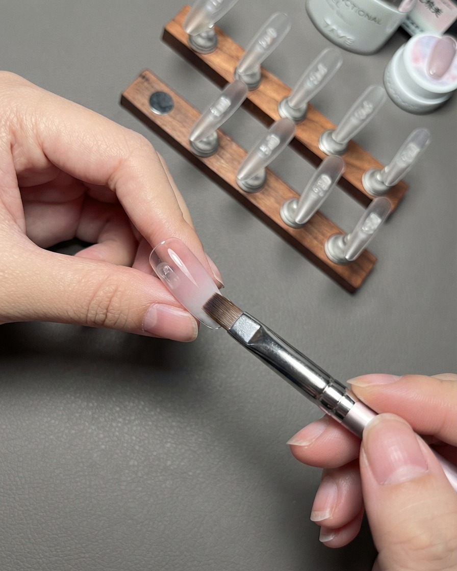 A brush feathering the nude gradient layer on a press-on nail.