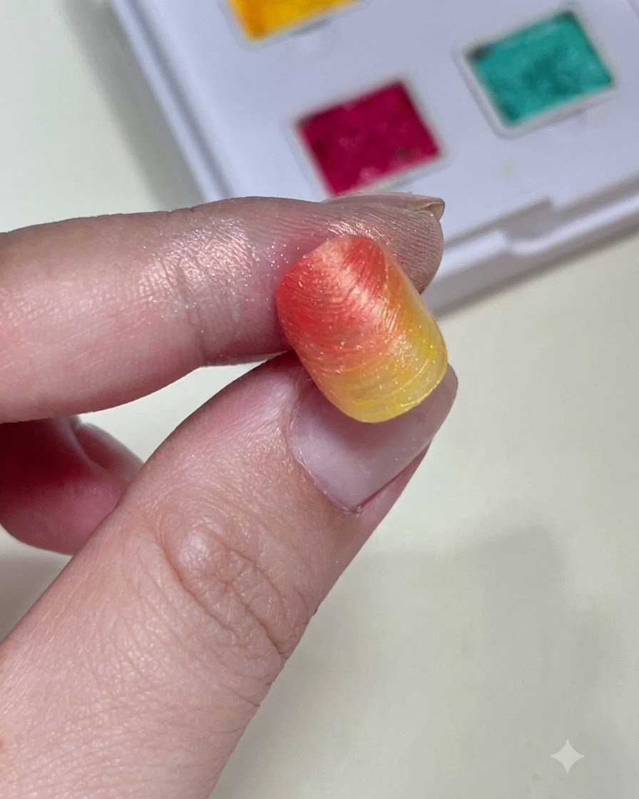A close-up holding a textured gradient nail tip showing the shape and color of the background before charms are added.