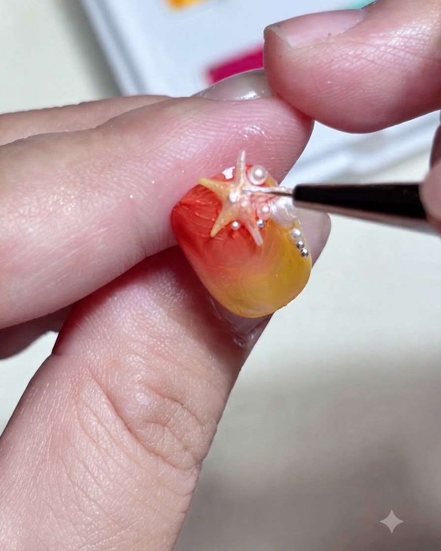 A fine brush adding detailed white dots and highlights onto a 3D starfish charm mounted on a gradient nail.
