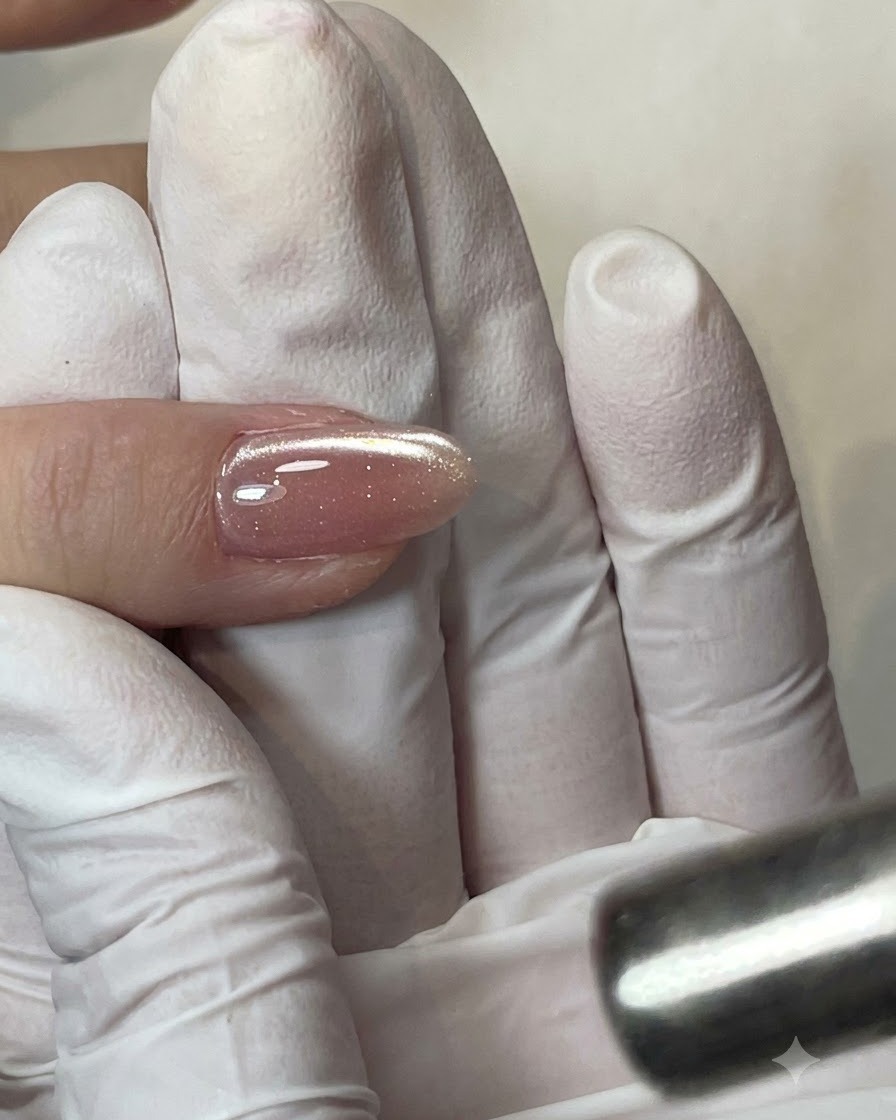 A flat gel brush applying a clear layer of base coat onto the nail plate.