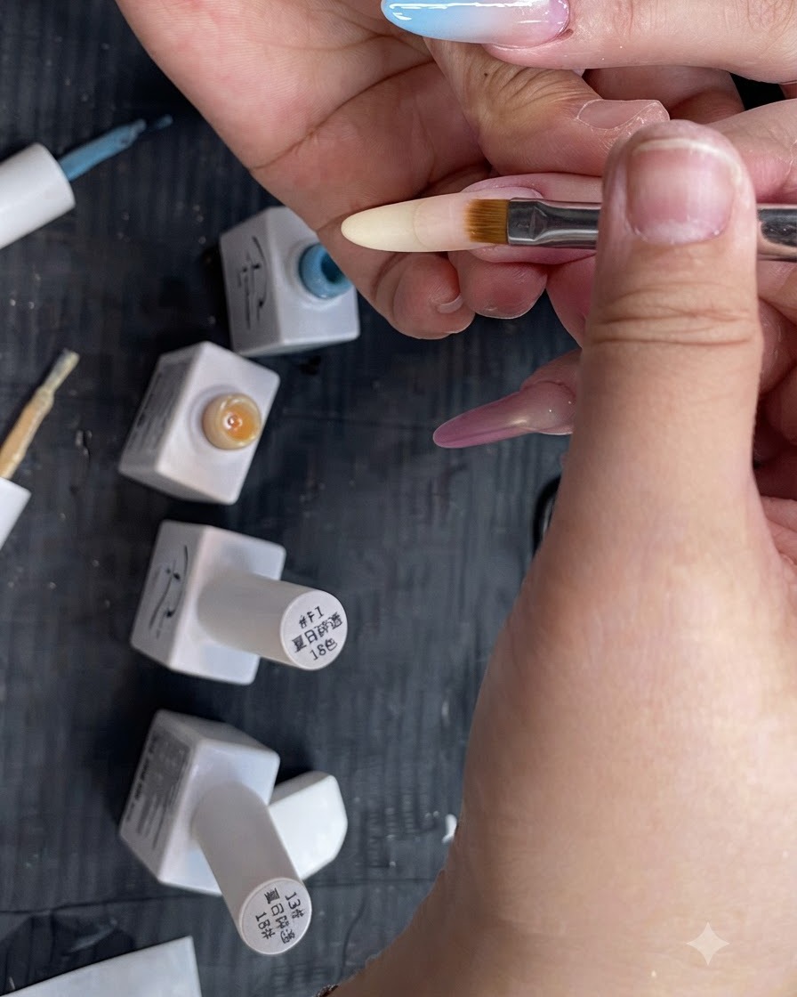 A flat ombre nail brush blending a translucent yellow gradient downward on a long almond-shaped fingernail.