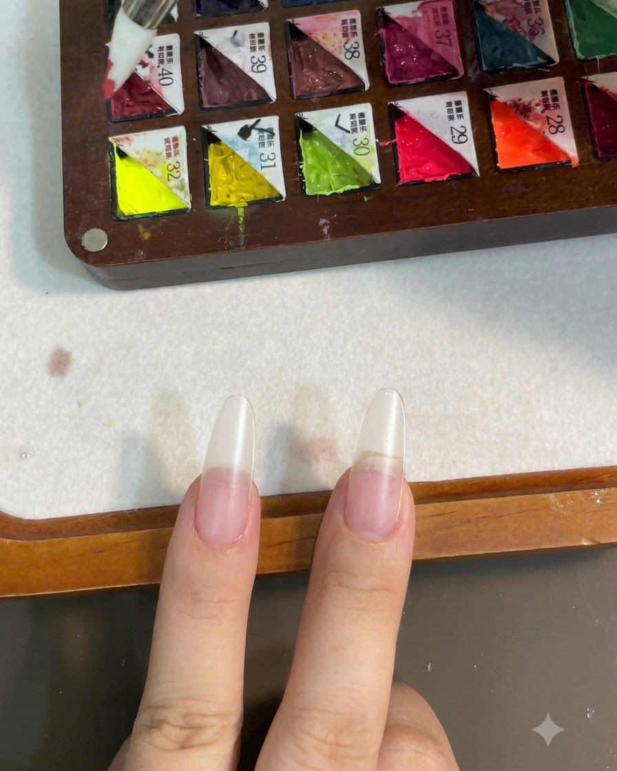 A silicone brush picking up pink gel color from a compartmentalized palette.