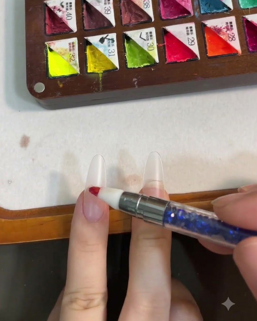 A silicone tool dabbing pink gel onto the center of a nail to form a blush effect.