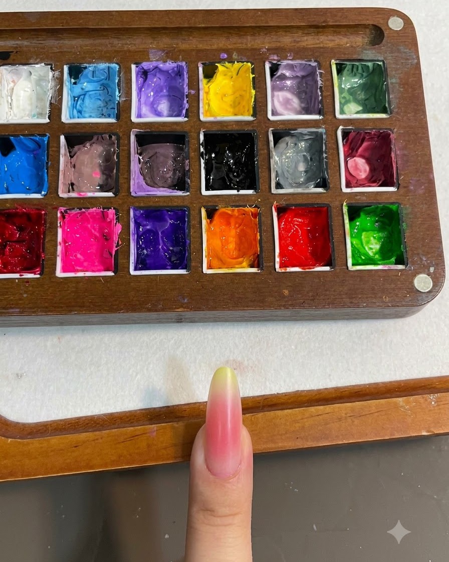 A close up of a nail with a pink and yellow gradient being cured under a nail lamp.