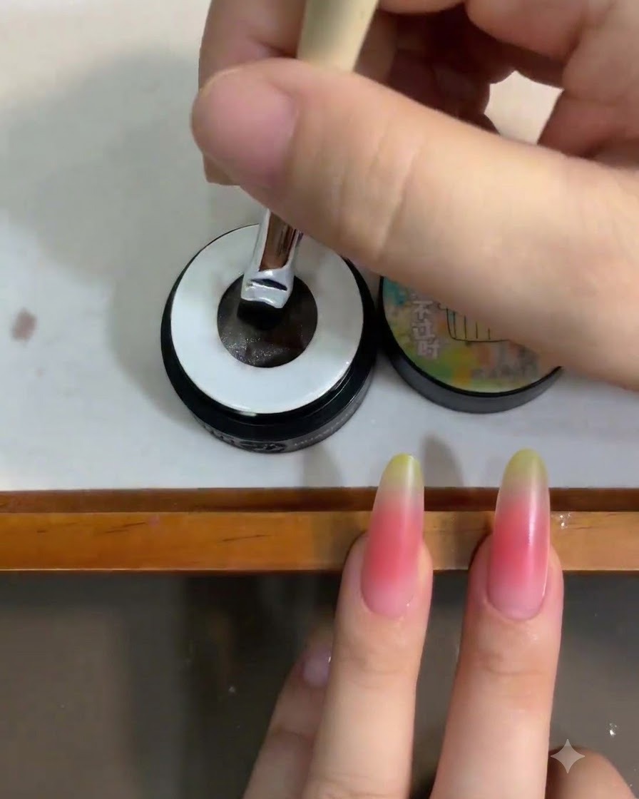 A nail brush being dipped into a small jar of translucent white cat eye gel polish.