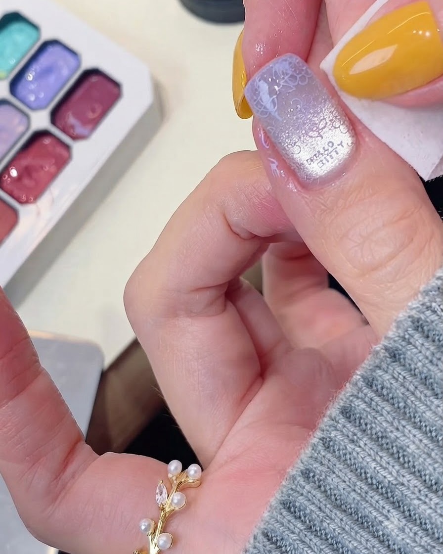 A wipe cleaning up excess gel around the edges of a manicured nail.