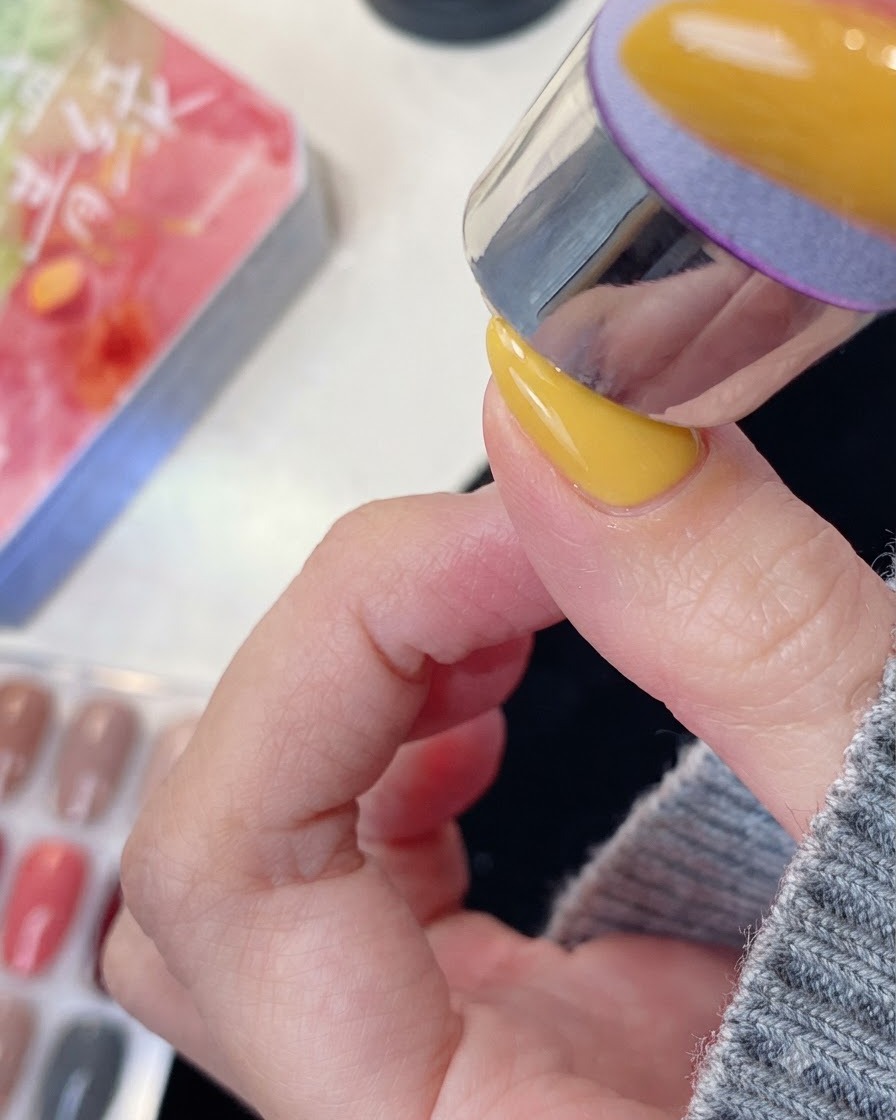 A manicured finger positioned under a UV or LED nail lamp for curing.