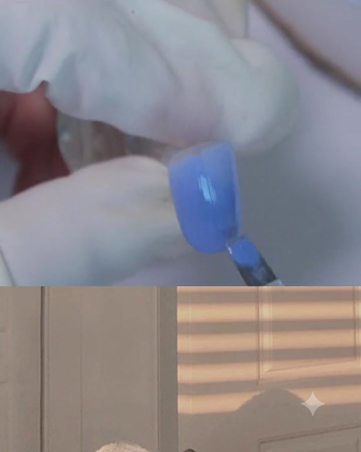 A flat gel brush applying a coat of blue-purple gel onto a nail surface.
