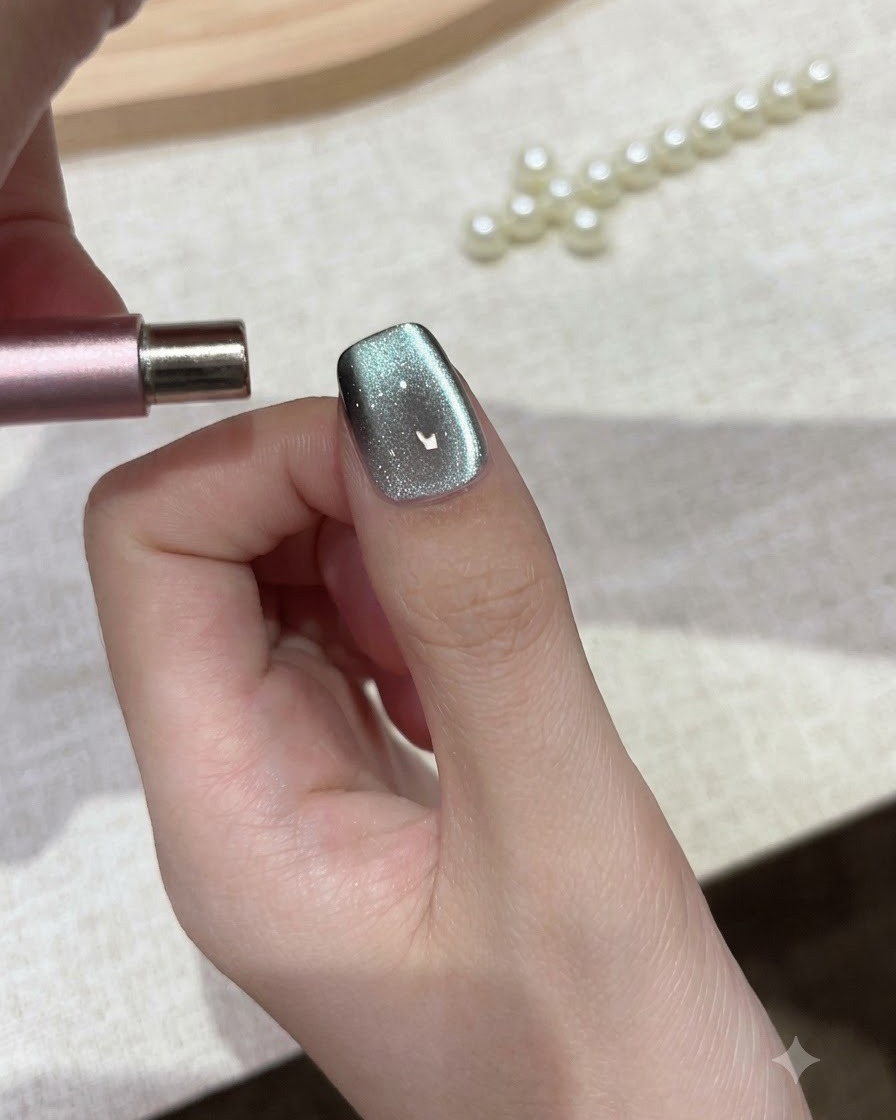 A cylindrical magnet held parallel to the nail tip to shape cat eye gel particles.