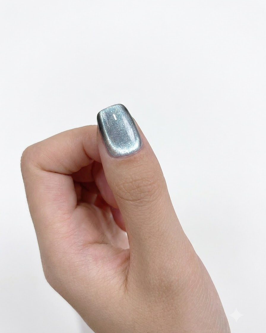 A close-up view of a cylindrical magnet held precisely against the left side of a painted nail.