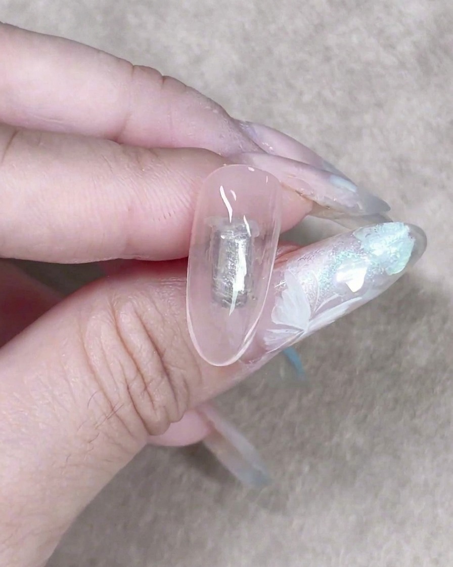 A small makeup sponge gently patting a sheer milky gel onto a nail to create a soft textured background.