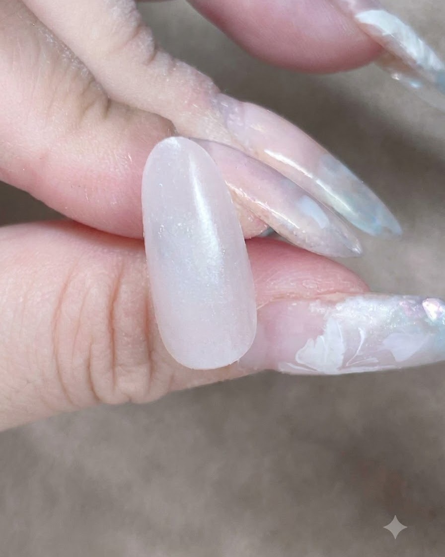 A close-up view of a makeup sponge dabbing along the cuticle and sidewall to blend a gel base layer.