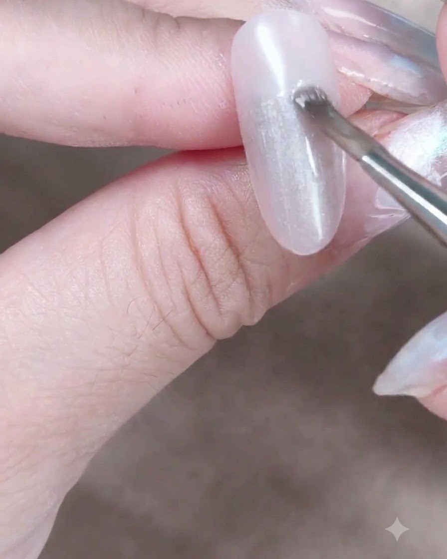 A cylindrical magnet held close to a wet cat-eye gel nail to pull and shift the magnetic shimmer particles.