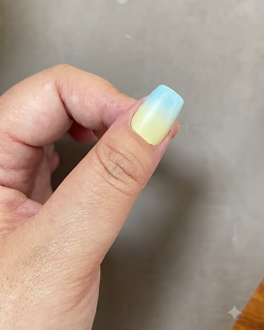 A fingernail with a blue and yellow gradient curing inside a UV LED nail lamp.