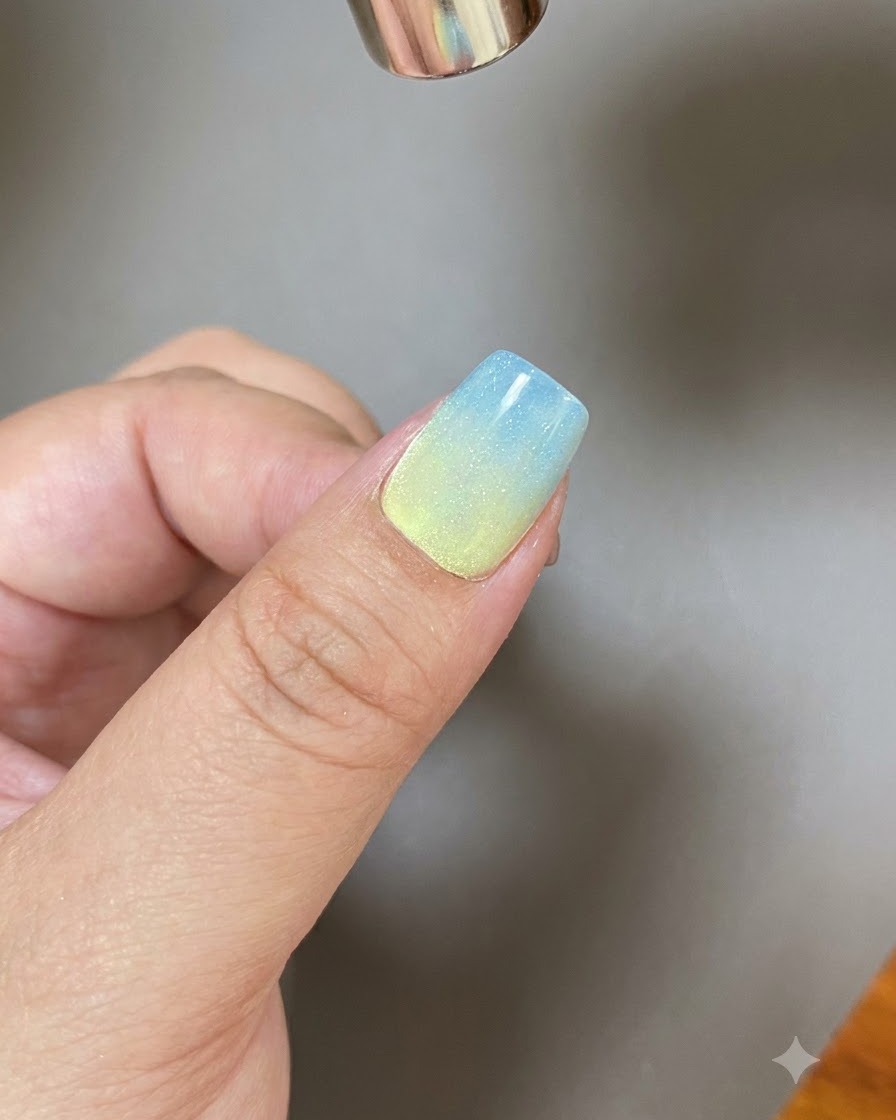 A magnetic tool shaping a wide streak of light across a sparkling gel-coated nail.