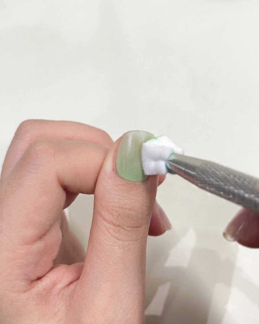 A thumb positioned underneath a compact mini UV/LED flashlight to cure gel polish.