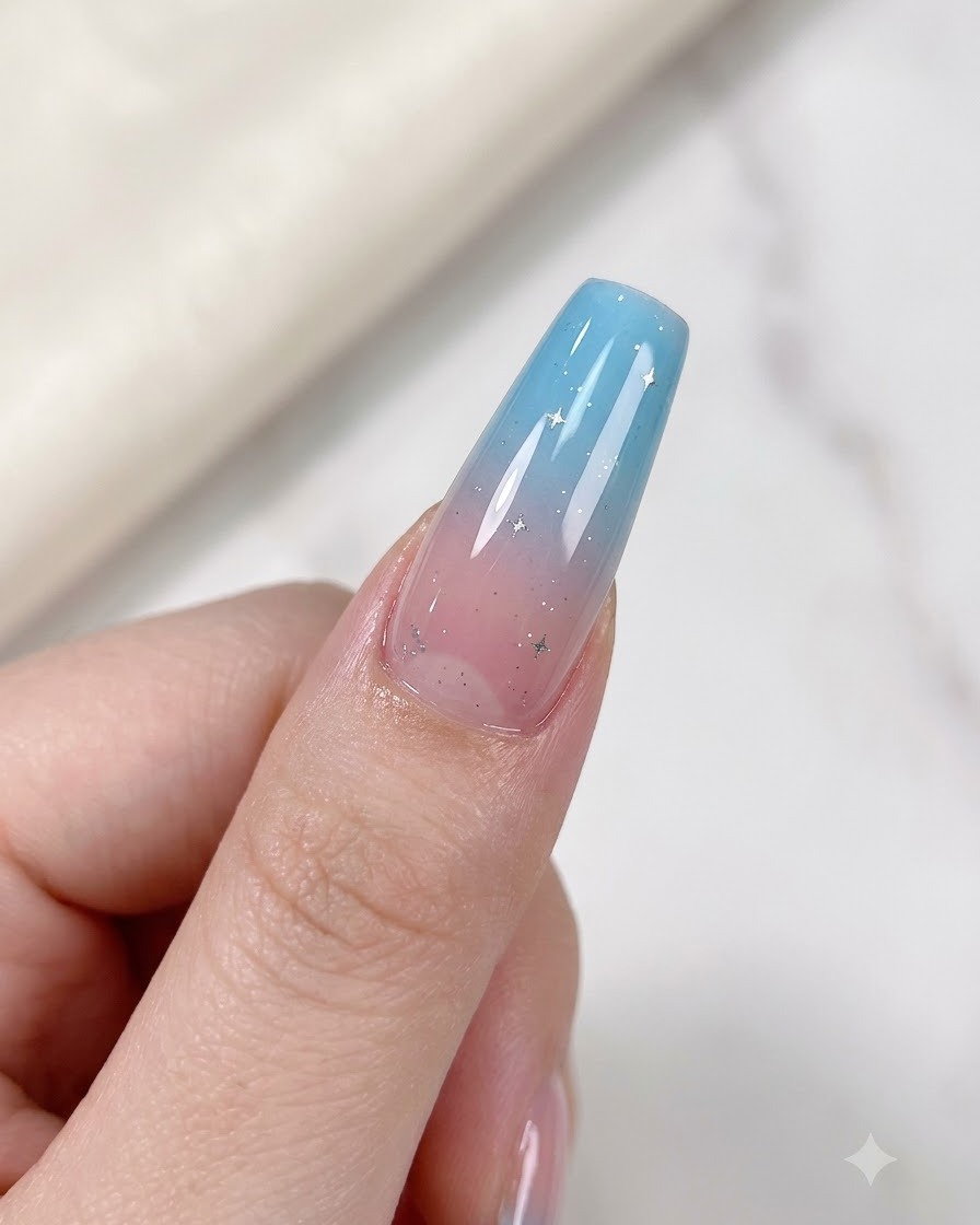 A finger with a gradient nail featuring delicate silver star accents placed under a UV/LED curing lamp.