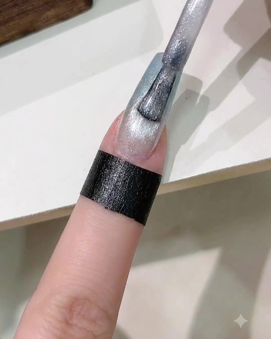 A brush applying a coat of silver magnetic cat eye gel polish onto the gradient nail.