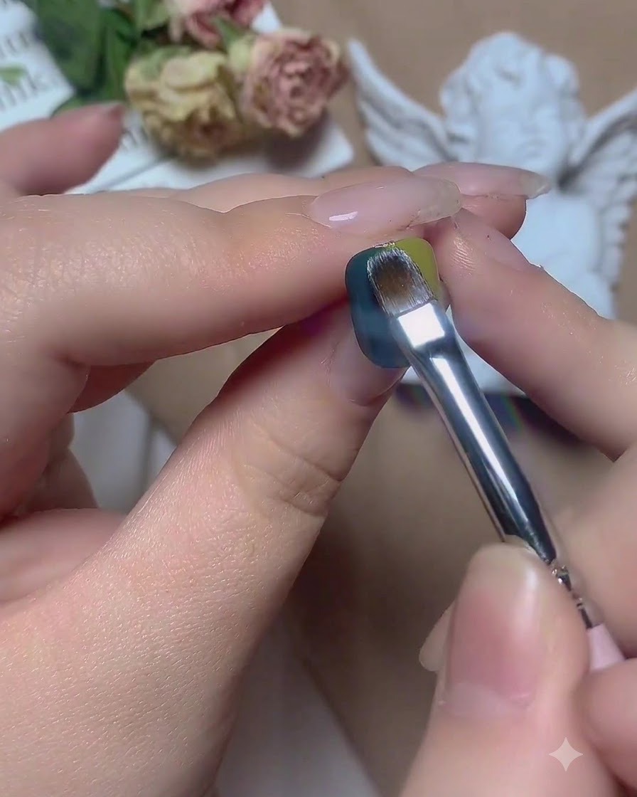 A brush sliding horizontally across the center boundary of green and blue gel.