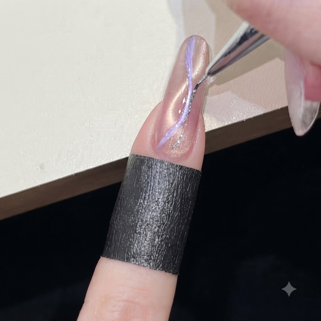 A fine liner brush drawing a thin silver glitter line over a pink cat-eye nail design.