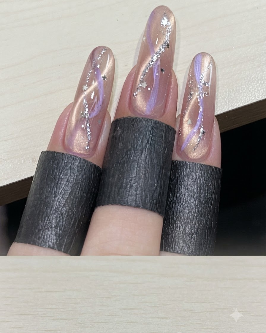 A multi-finger view displaying finished ribbon cat-eye manicures embellished with silver star sequins.