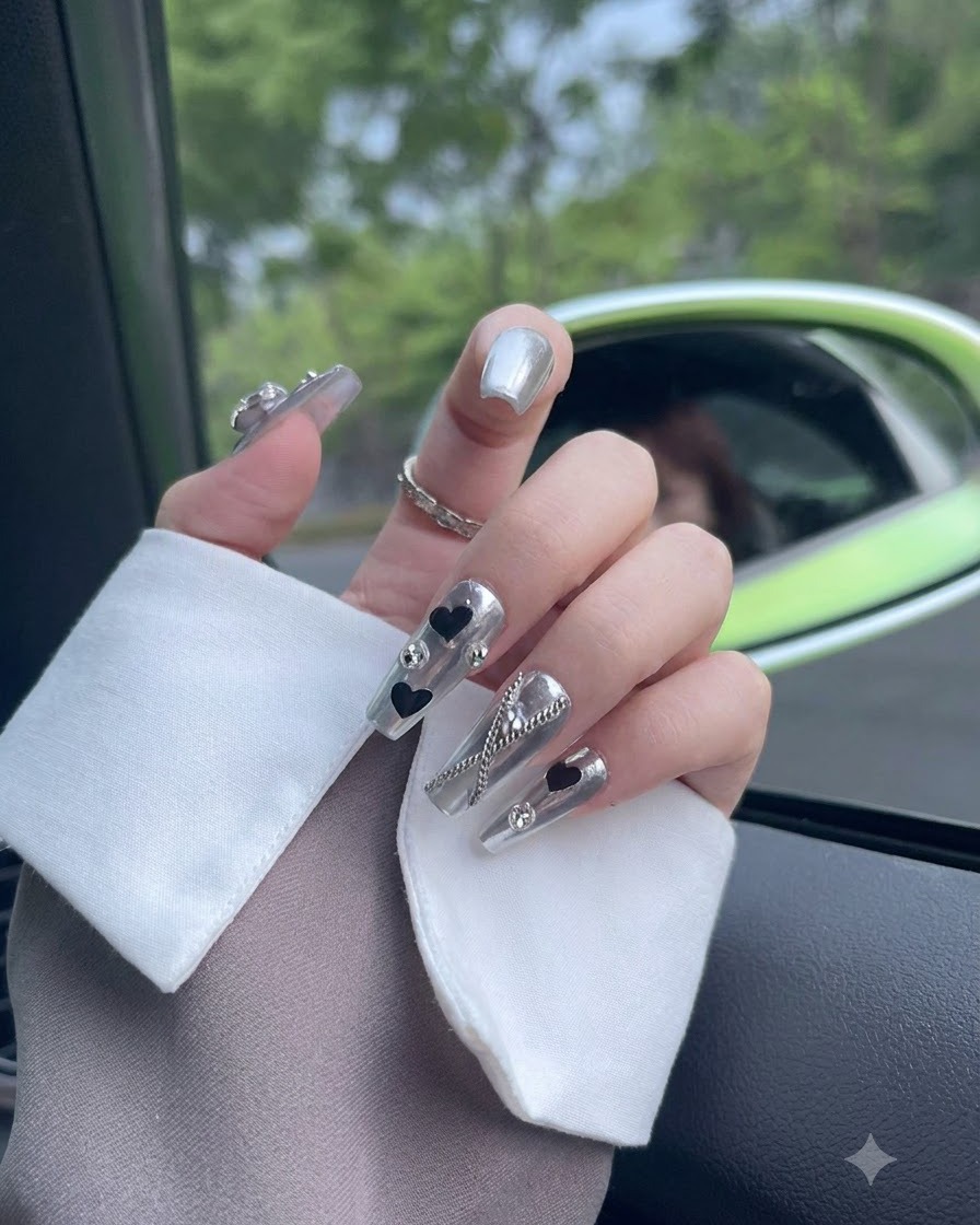 A close-up view focusing on a thumb nail adorned with a chrome finish and a sparkling crystal element.
