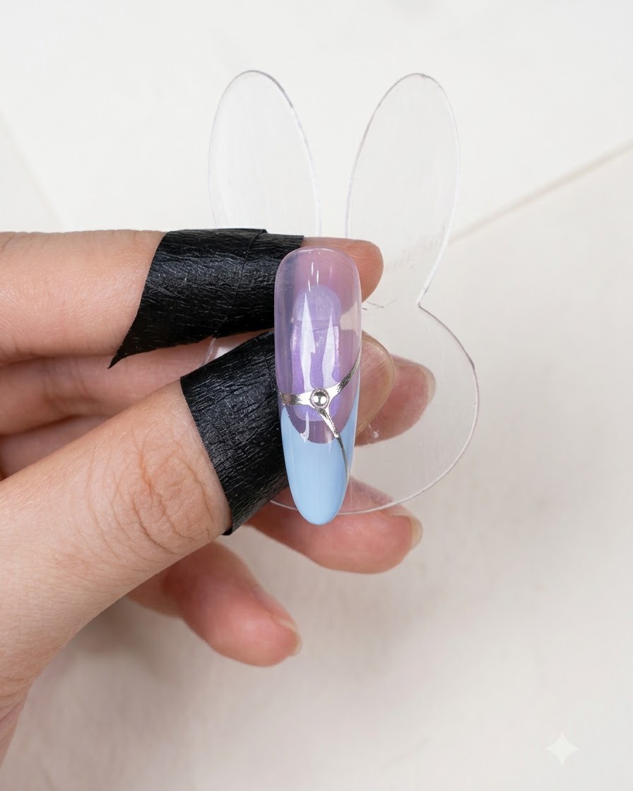 A finished nail display showing a completed French manicure design with a silver accent line and a central rhinestone.