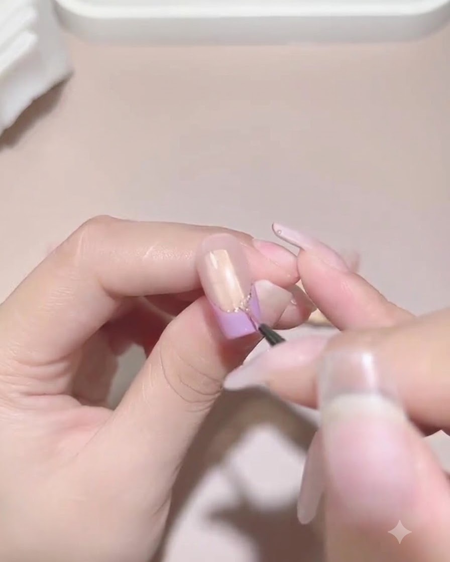 A fine detailing brush carefully applying sealing gel around the base of attached pearls and rhinestones on a manicured nail.