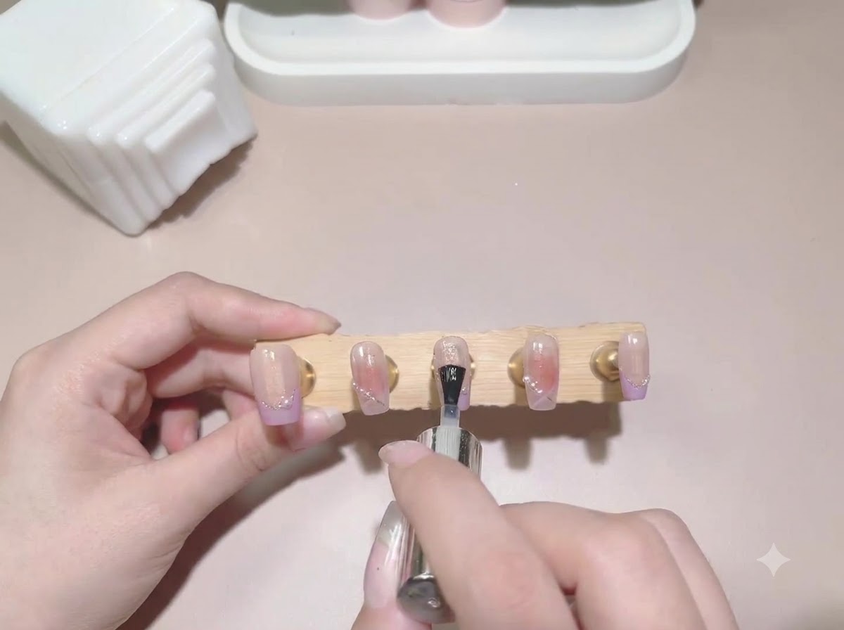 A top coat brush being applied across a display stand of finished painted false nails.