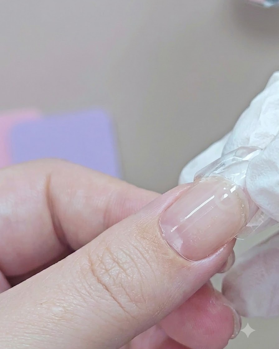 A fingernail with a dual form attached undergoing a handheld blue UV lamp cure.