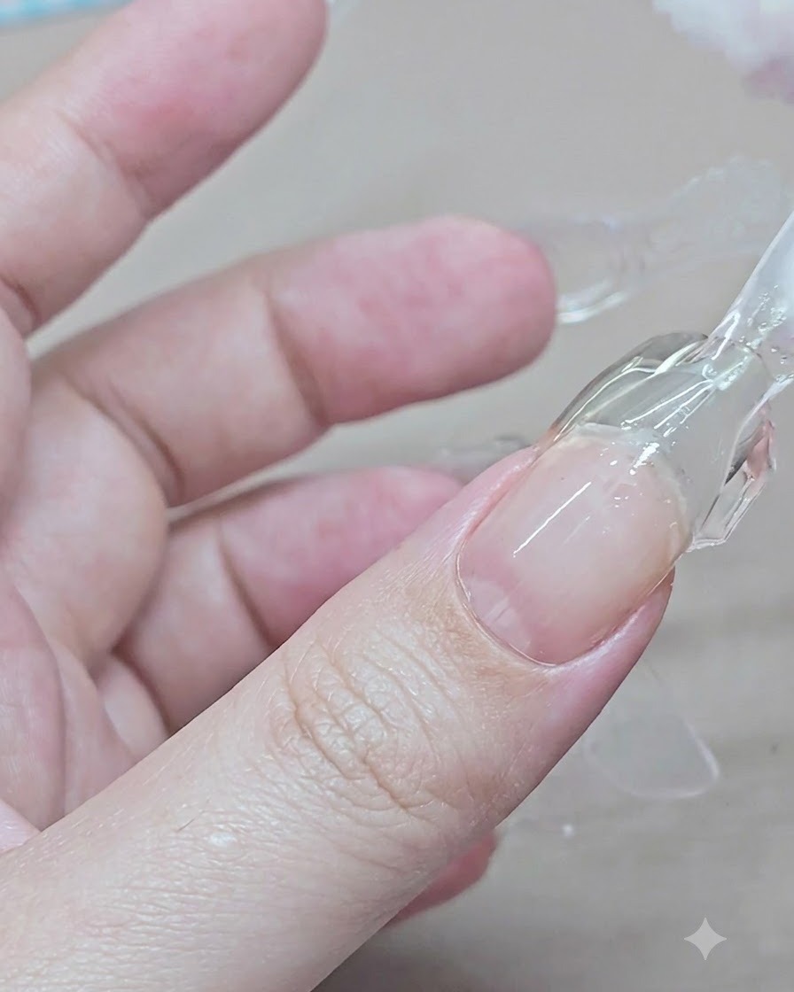 A hand pinching and lifting a clear plastic dual form off a cured gel extension on the index finger.