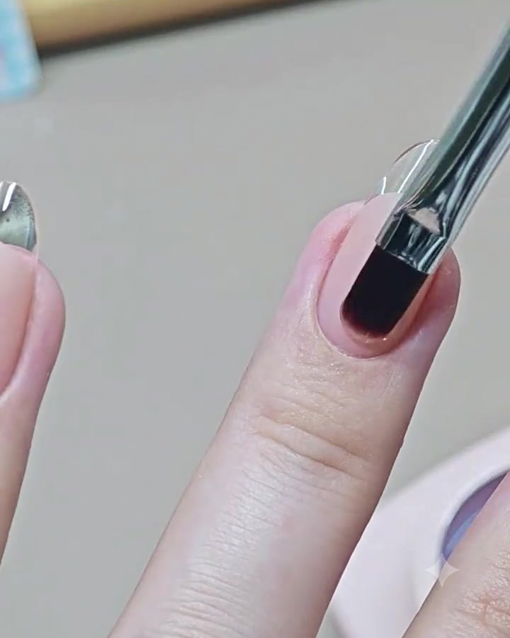A nail art brush applying a glossy clear top coat onto a finished French manicure nail.