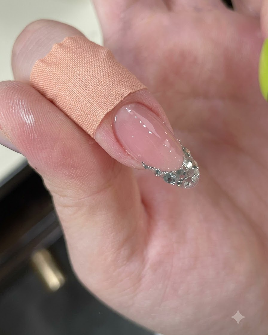 A finger being wiped clean with a cleansing pad, showing a textured silver glitter French tip.
