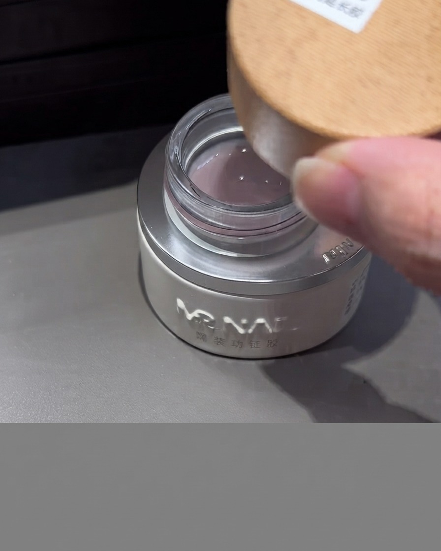 A jar of milk extension gel with a wooden lid being opened, showing the milky translucent gel inside.