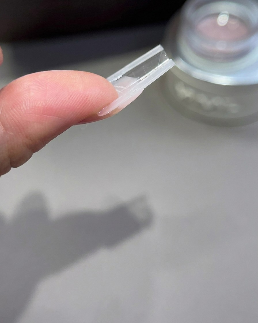 An inverted view of a nail extension mold showing the profile and arch structure of the gel.