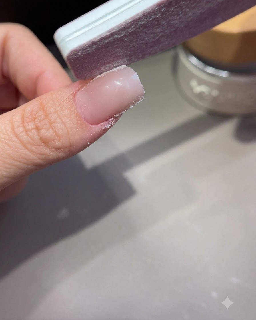 A hand file shaping and smoothing the sidewalls of an extended acrylic or gel nail.
