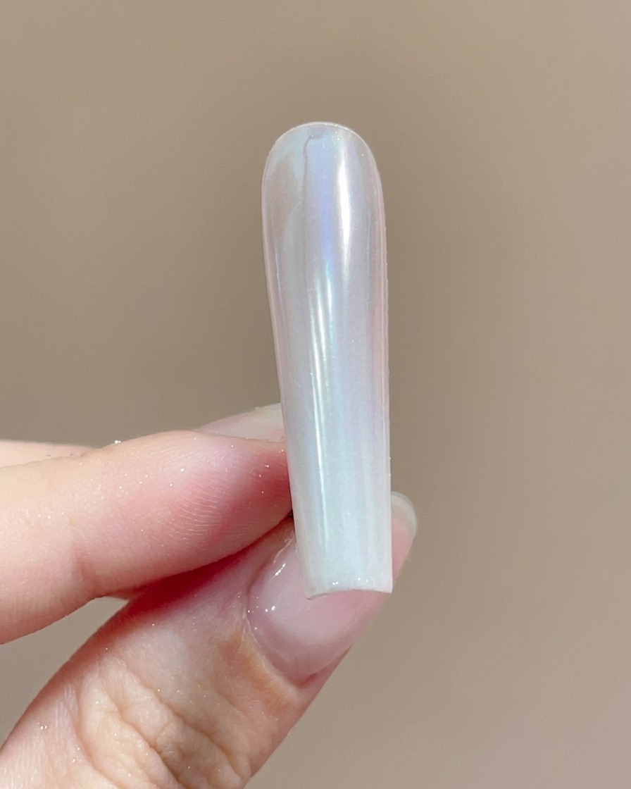 A brush applying a clear top coat over a shimmering chrome powder-coated nail.