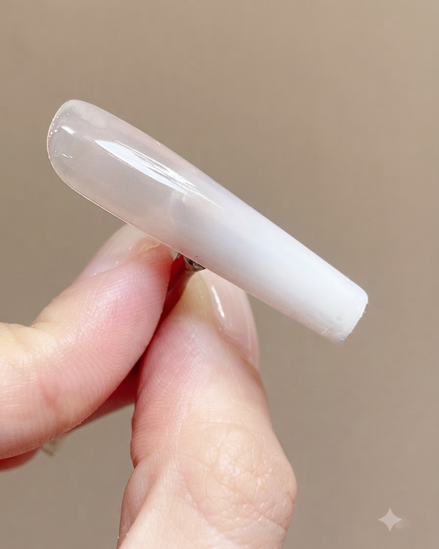 A smooth, glossy cured nail showing a clear reflection of light across its surface.