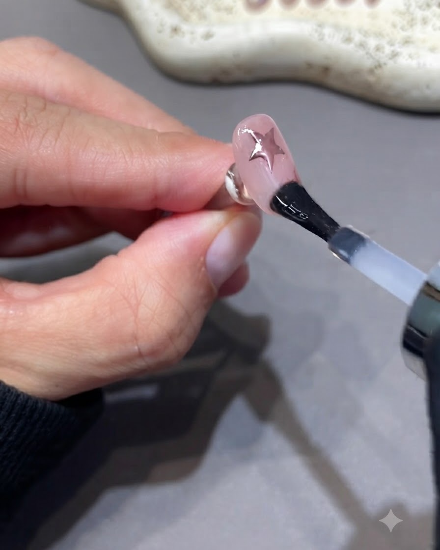 A brush applying an extra layer of sealing top coat over a manicured nail.