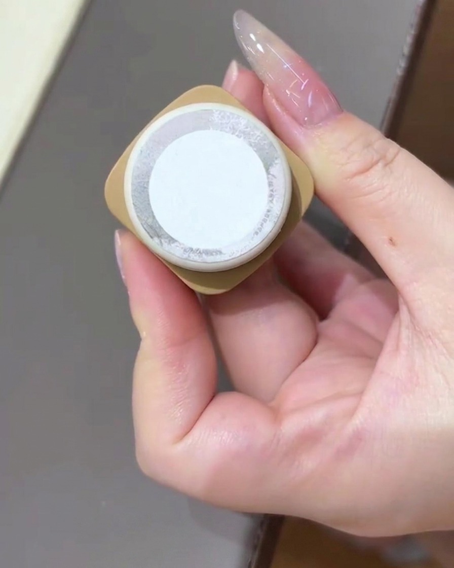 A hand holding a bottle of cat eye gel polish facing the camera.
