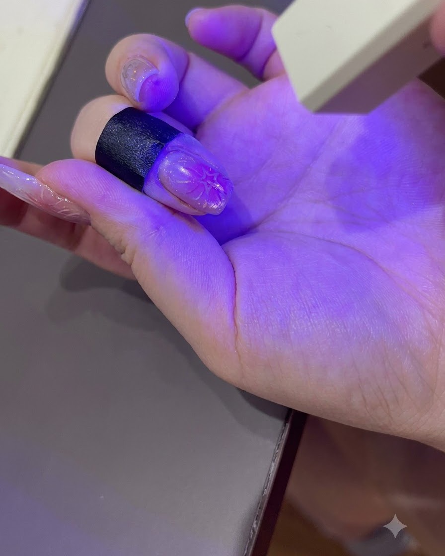 A manicured hand curing under the purple light of a portable UV/LED nail lamp.