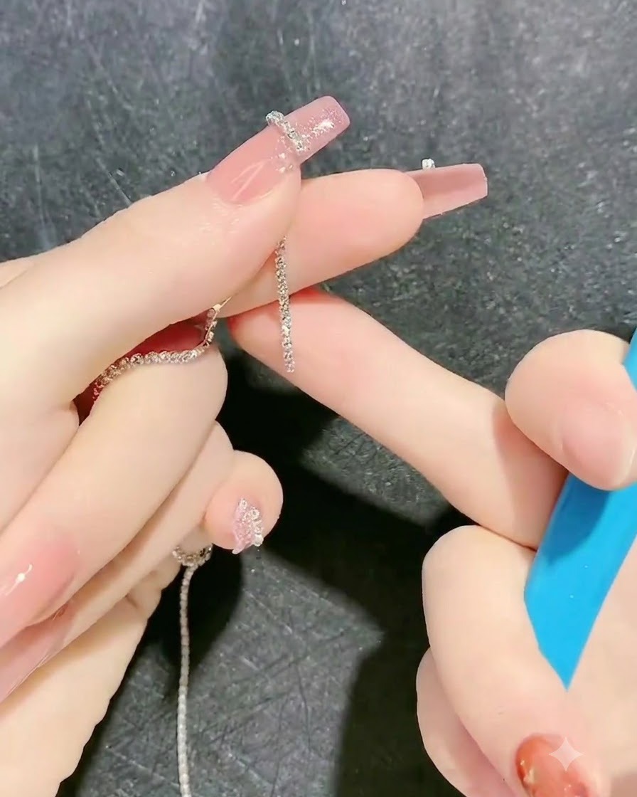 A tool placing a rhinestone chain strip onto the tacky gel outline on a finger.