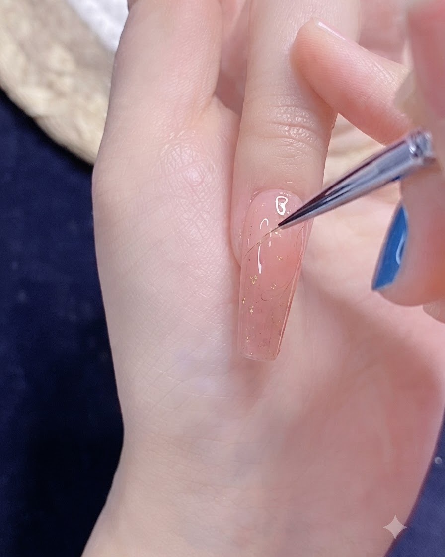 A fine nail art brush drawing a delicate half heart outline in gel on a pink-polished nail.