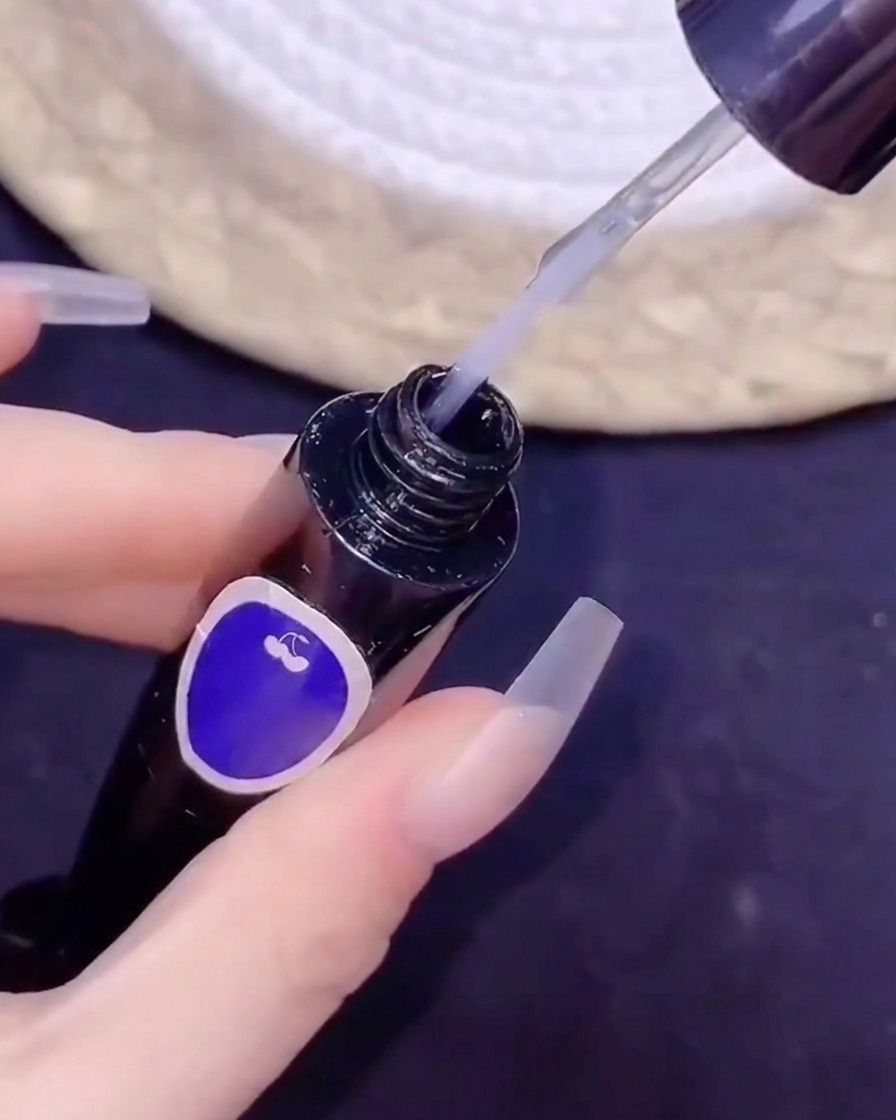 A fine brush dipping into a bottle of no-wipe top coat during a nail art procedure.