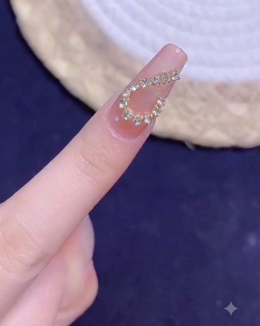 A manicured finger with a golden chain heart design shown close-up under lighting after curing.
