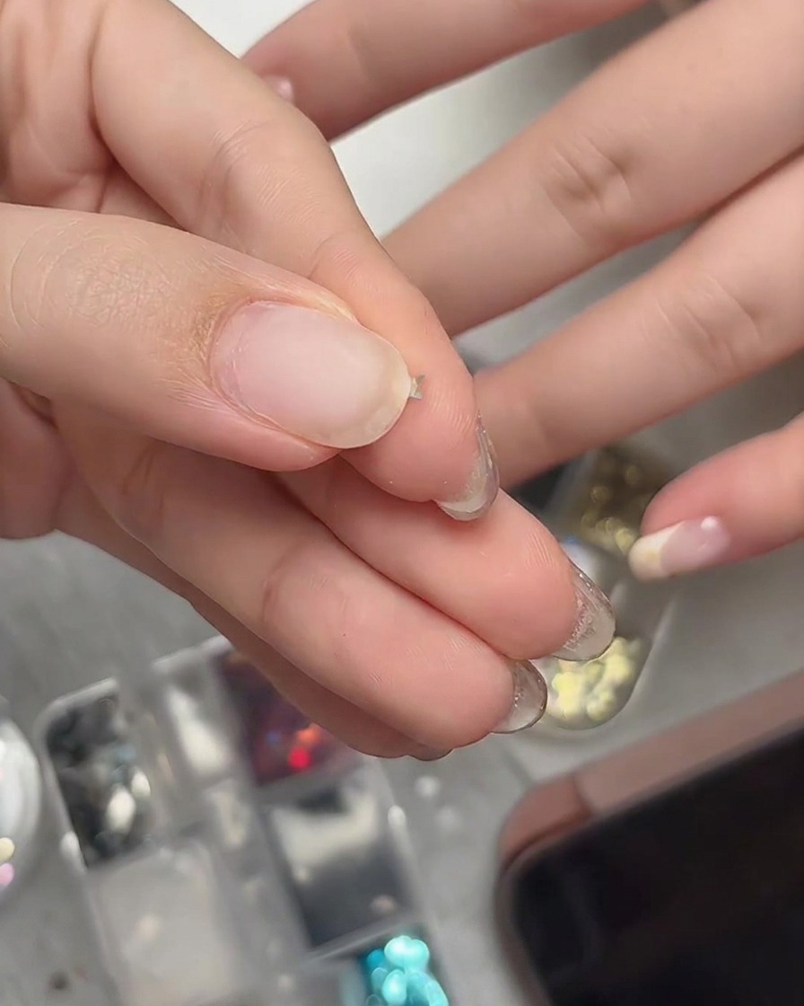 Fingers gently pinching a tiny star glitter piece to bend it into a curved three-dimensional shape.