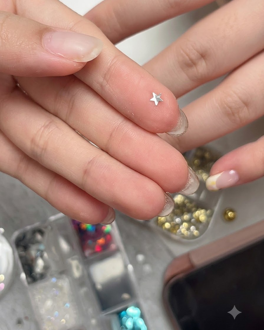 A curved metallic silver star glitter piece resting on a fingertip, ready to be picked up.